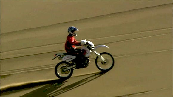 Тао Юнмінг на мотоциклі Suzuki DR 250 під час підйому на дюну
